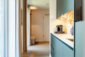 A modern kitchen with a coffee machine, a vase with flowers, and a view into the living area. - Wind Force 7 - Sea State. Sauna. Patio. Dog-Friendly (Grömitz)