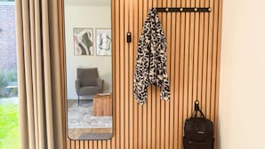 A room with a wooden slat wall, a bench, a coat rack, a mirror, and a hanging bag. - Wind Force 7 - Sea State. Sauna. Patio. Dog-Friendly (Grömitz)