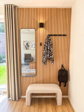 A room with a wooden slat wall, a bench, a coat rack, a mirror, and a hanging bag. - Wind Force 7 - Sea State. Sauna. Patio. Dog-Friendly (Grömitz)