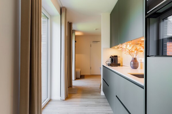 A modern kitchen with a built-in oven, a coffee machine, and a vase on the counter.