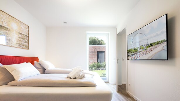 A hotel room with a bed, a window, and a wall-mounted TV. - Wind Force 7 - Sea State. Sauna. Patio. Dog-Friendly (Grömitz)