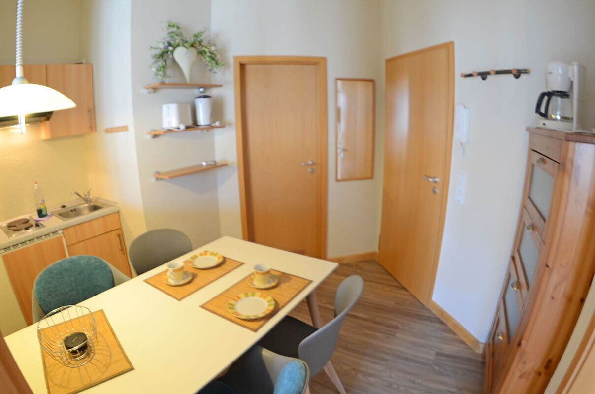 Eine kleine Küche mit Esstisch für zwei Personen, einem Spülbecken und einem Schrank.