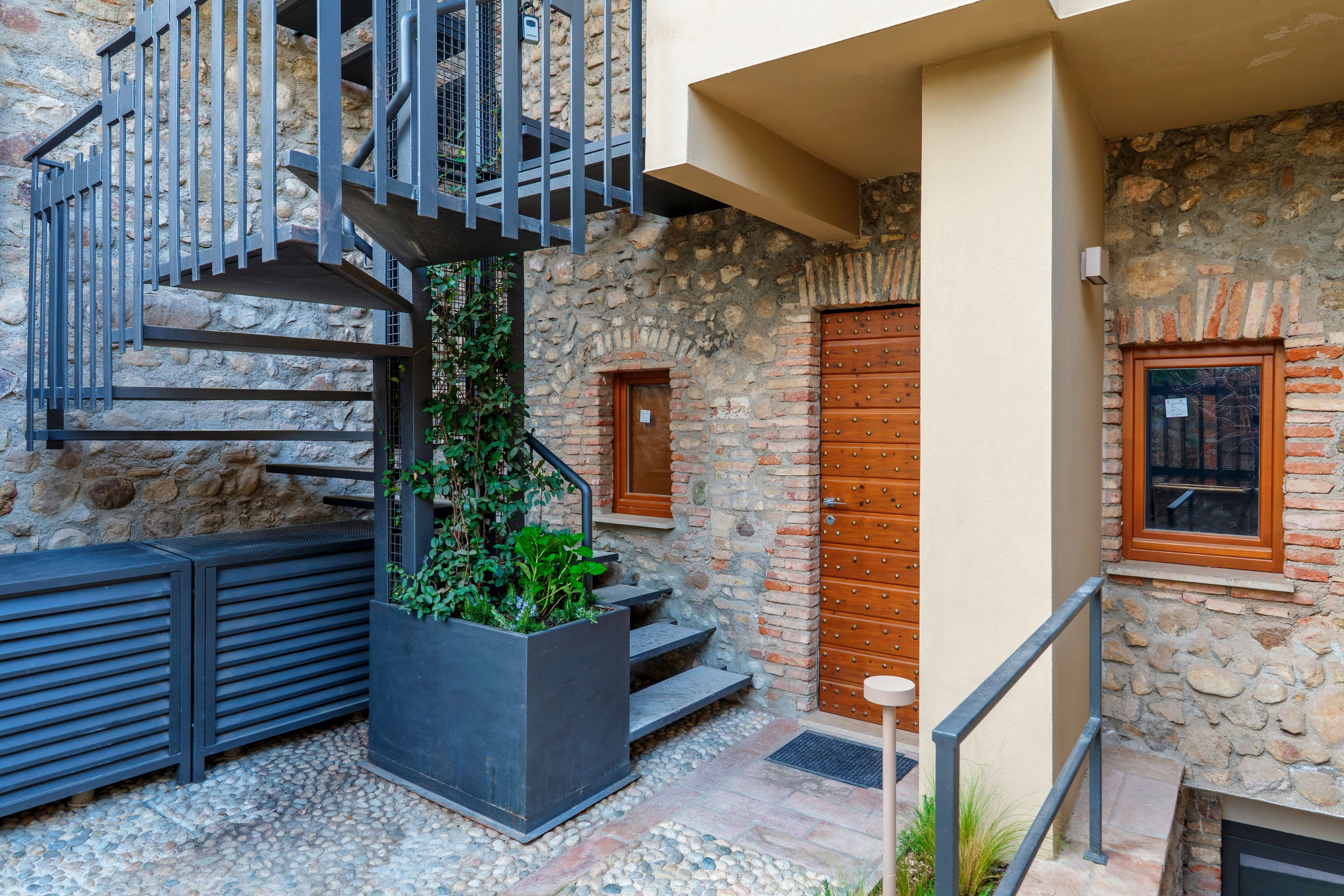Un edificio de piedra con una escalera de metal, una puerta de madera y un ventanal.