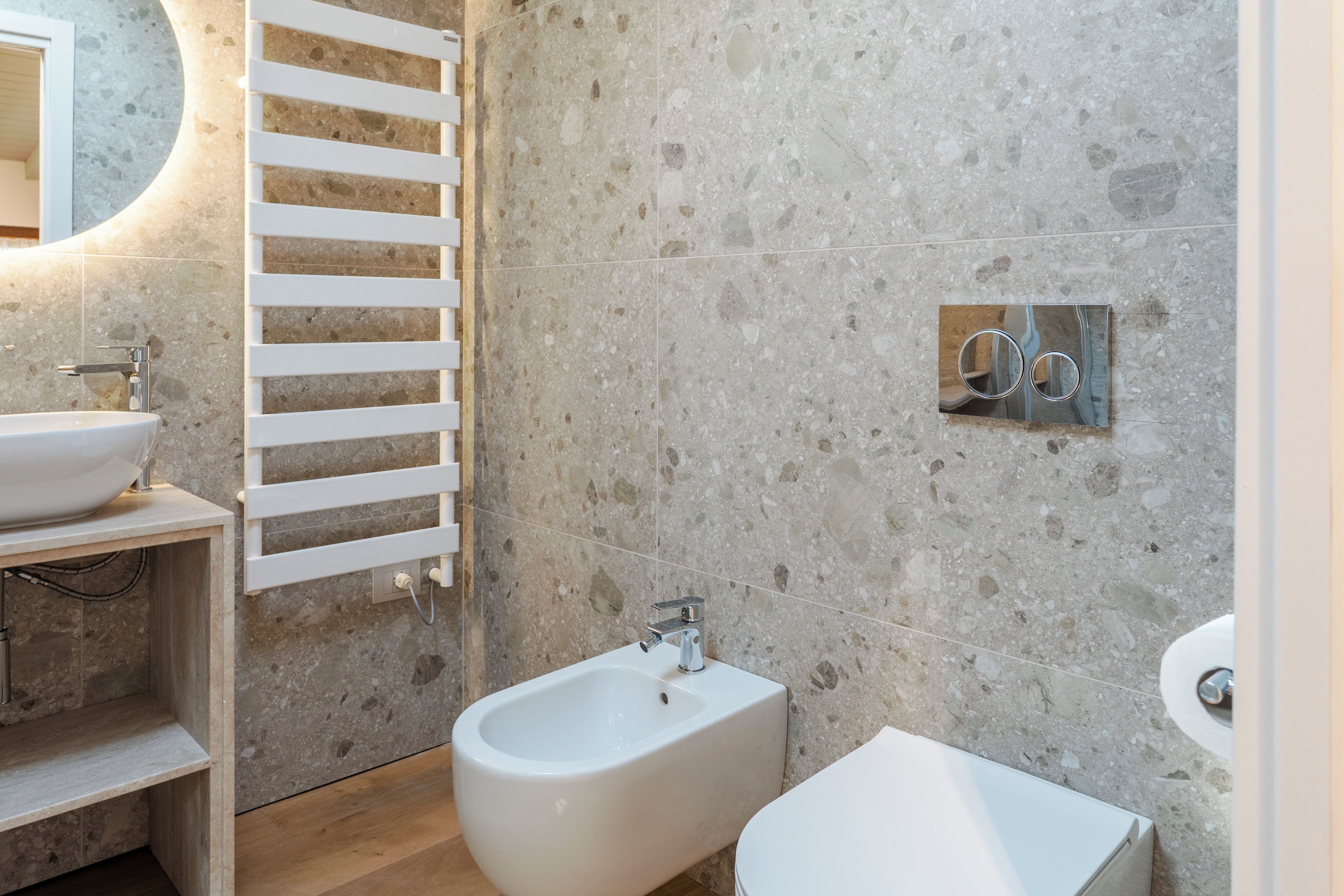 A modern bathroom with a bidet, a sink, and a mirror.