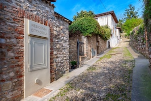 A narrow cobblestone street with stone buildings, a sign reading 'RESIDENZA CITTADELLA', and a door with a vent. - Residenza Cittadella (Lonato del Garda)