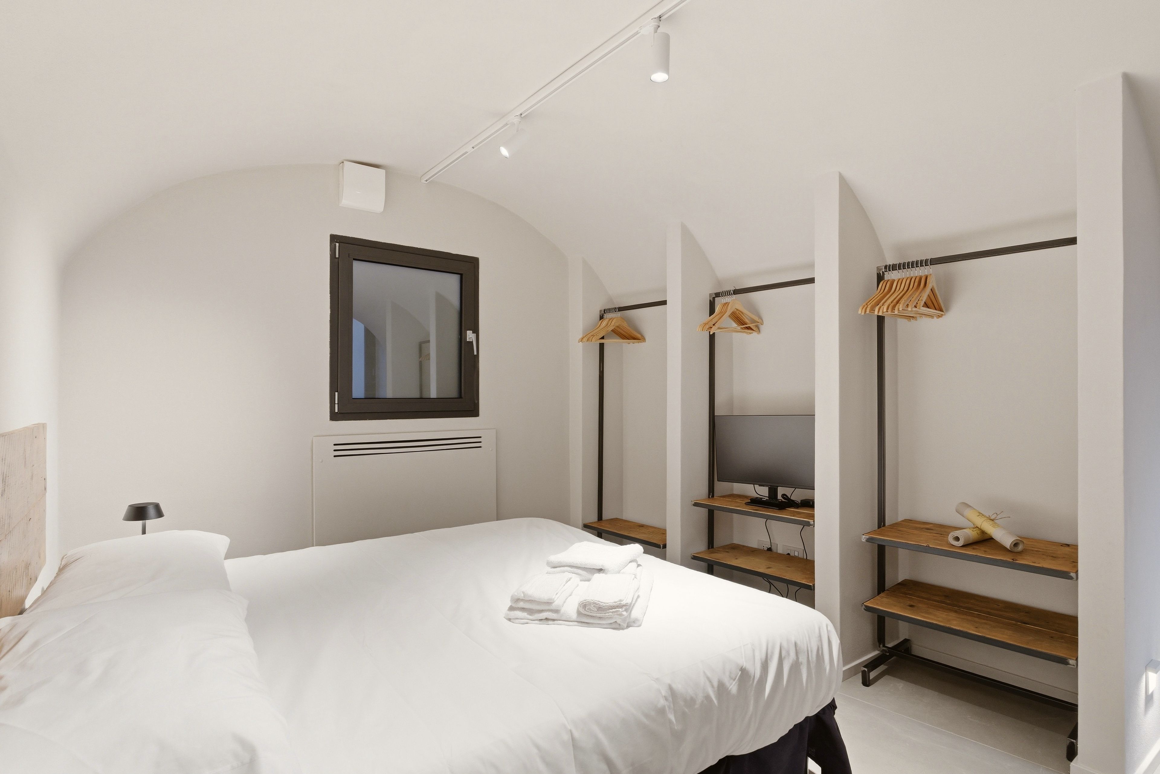 Ein modernes Schlafzimmer mit einem Bett, einem Spiegel, einem Fernseher und einem Holzregal.