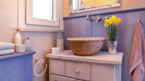 A bathroom with a wooden vanity, a large bowl sink, a mirror, a towel rack, and a vase with yellow flowers. - BLUE OCEAN-VIEW APARTMENT, terrace, air conditioning, internet, and parking space (San Vincenzo)