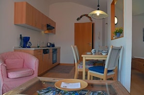 A compact living space with a kitchenette, a dining area, and a seating area with a sofa and chairs. - Juliusruh Seaside Resort, 2nd floor, town center, quiet location, right on the sandy beach (Juliusruh)