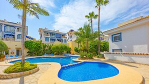 A resort with a swimming pool, palm trees, and a clear blue sky. - Hanami Apartment - Plusholidays (Calpe / Calp)