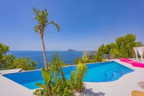A swimming pool with a view of the sea, surrounded by greenery and a clear sky. - Villa Infinitysea - PlusHolidays (Altea)