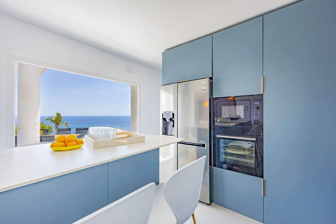 A modern kitchen with a view of the ocean, a refrigerator, and a dishwasher.