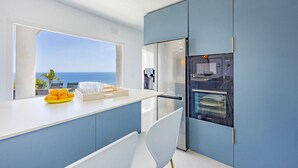 Eine moderne Küche mit Meerblick, inklusive Kühlschrank und Geschirrspüler.