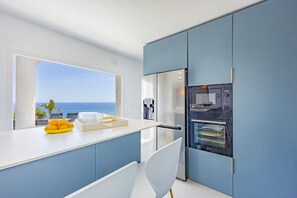 Eine moderne Küche mit Meerblick, inklusive Kühlschrank und Geschirrspüler.