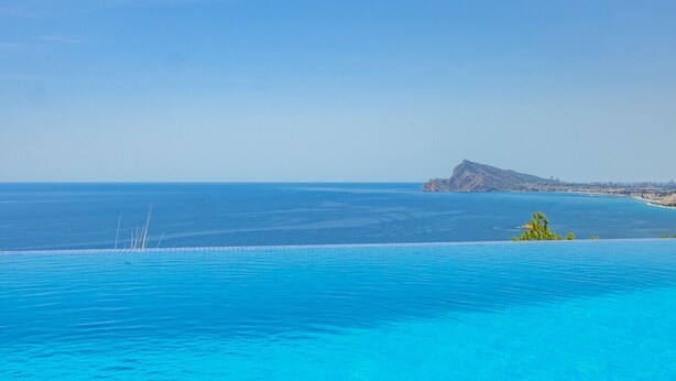 Ein Infinity-Pool mit freiem Blick auf den Ozean und einer entfernten Insel.