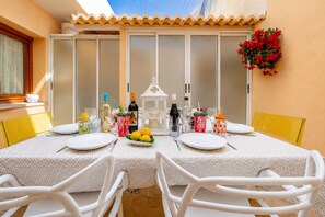 An outdoor dining area with a table set for four, surrounded by white chairs, and a decorative lantern in the center. - Calasanz Apartment - Plusholidays (Calpe / Calp)