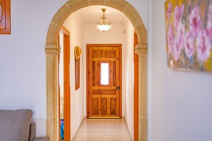 A hallway with a wooden door, a chandelier, and a painting on the wall. - Calasanz Apartment - Plusholidays (Calpe / Calp)