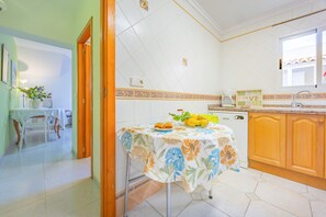 A kitchen with a dining table, a coffee maker, and a fruit bowl. - Calasanz Apartment - Plusholidays (Calpe / Calp)