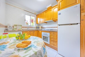 Eine Küche mit Holzausstattung, einem weißen Kühlschrank, einer Mikrowelle und einem Herd.