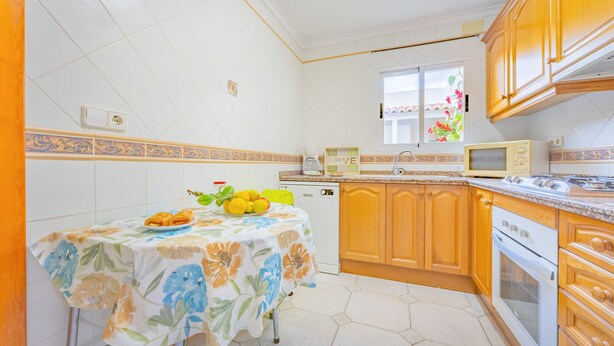 Uma cozinha com uma mesa posta para refeições, micro-ondas e fogão.