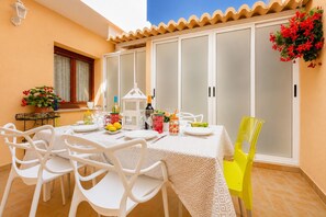 A dining area with a table set for four, white chairs, a white tablecloth, and a yellow chair. - Calasanz Apartment - Plusholidays (Calpe / Calp)