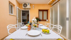 Uma área de refeições com uma mesa posta para seis pessoas, cadeiras brancas, toalha de mesa branca e um prato de limões.