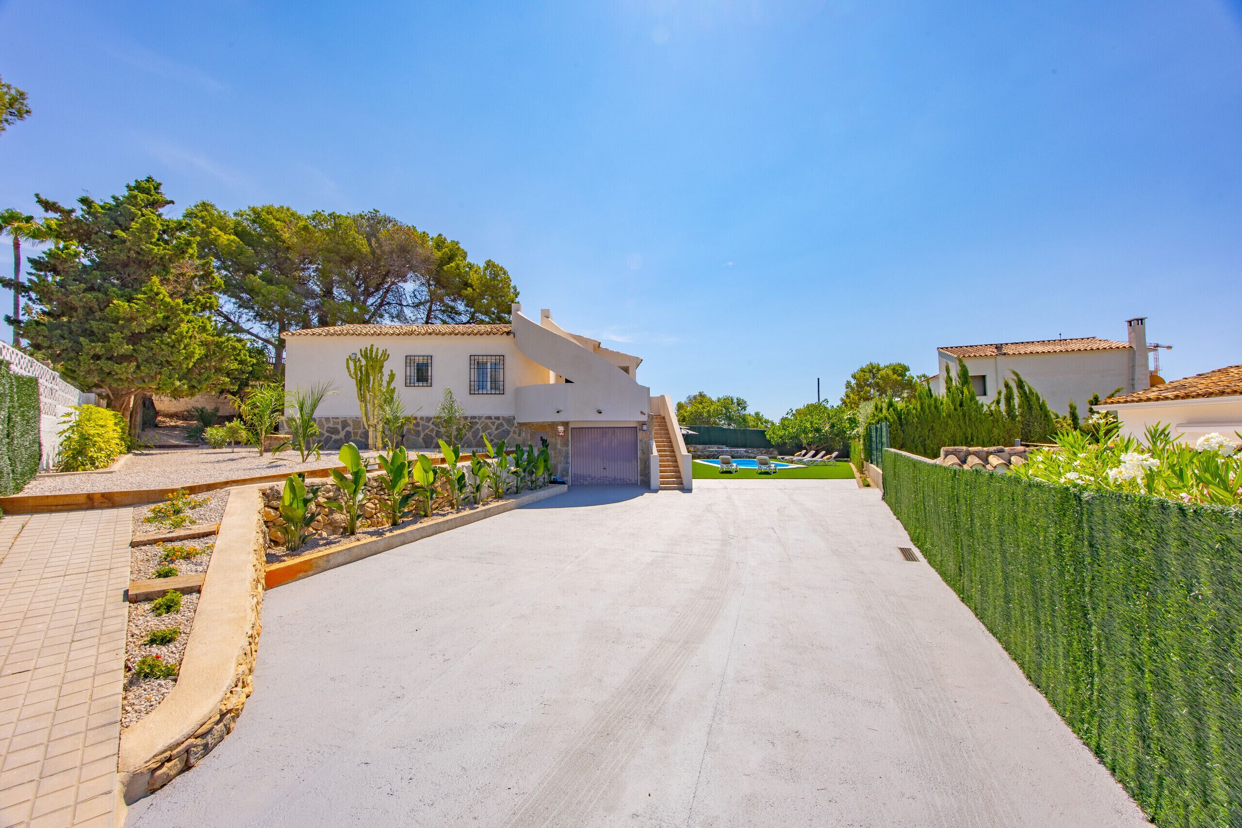 A residential property with a paved driveway, a swimming pool, and a well-maintained garden.