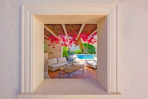 A framed view of a patio area with a white sofa, a coffee table, and a pool in the background. - Villa Descanso - Plusholidays (Calpe / Calp)
