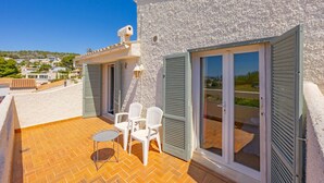 A balcony with a table and chairs, a white building with shutters, and a clear view of the surrounding area. - Villa Descanso - Plusholidays (Calpe / Calp)