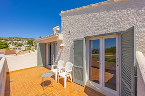A balcony with a table and chairs, a white building with shutters, and a clear view of the surrounding area. - Villa Descanso - Plusholidays (Calpe / Calp)