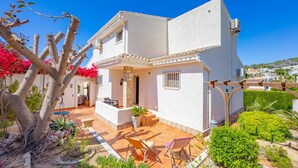 A white building with a patio area, outdoor seating, and a view of the surrounding landscape. - Villa Descanso - Plusholidays (Calpe / Calp)