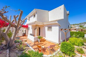 A white building with a patio area, outdoor seating, and a view of the surrounding landscape. - Villa Descanso - Plusholidays (Calpe / Calp)