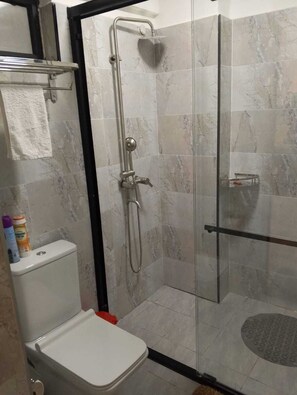 A bathroom with a glass-enclosed shower, a toilet, and a shelf with toiletries. - Modern One-Bedroom serviced apartment/ 9th floor/ gym, lift, balcony, city view (Nairobi)