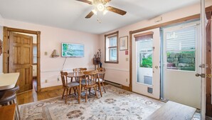 A dining area with a ceiling fan, a dining table with chairs, a patterned rug, and a door leading outside. - The Arlington GB: Charming Centrally Located Condo in Chautauqua Institution! (Chautauqua)