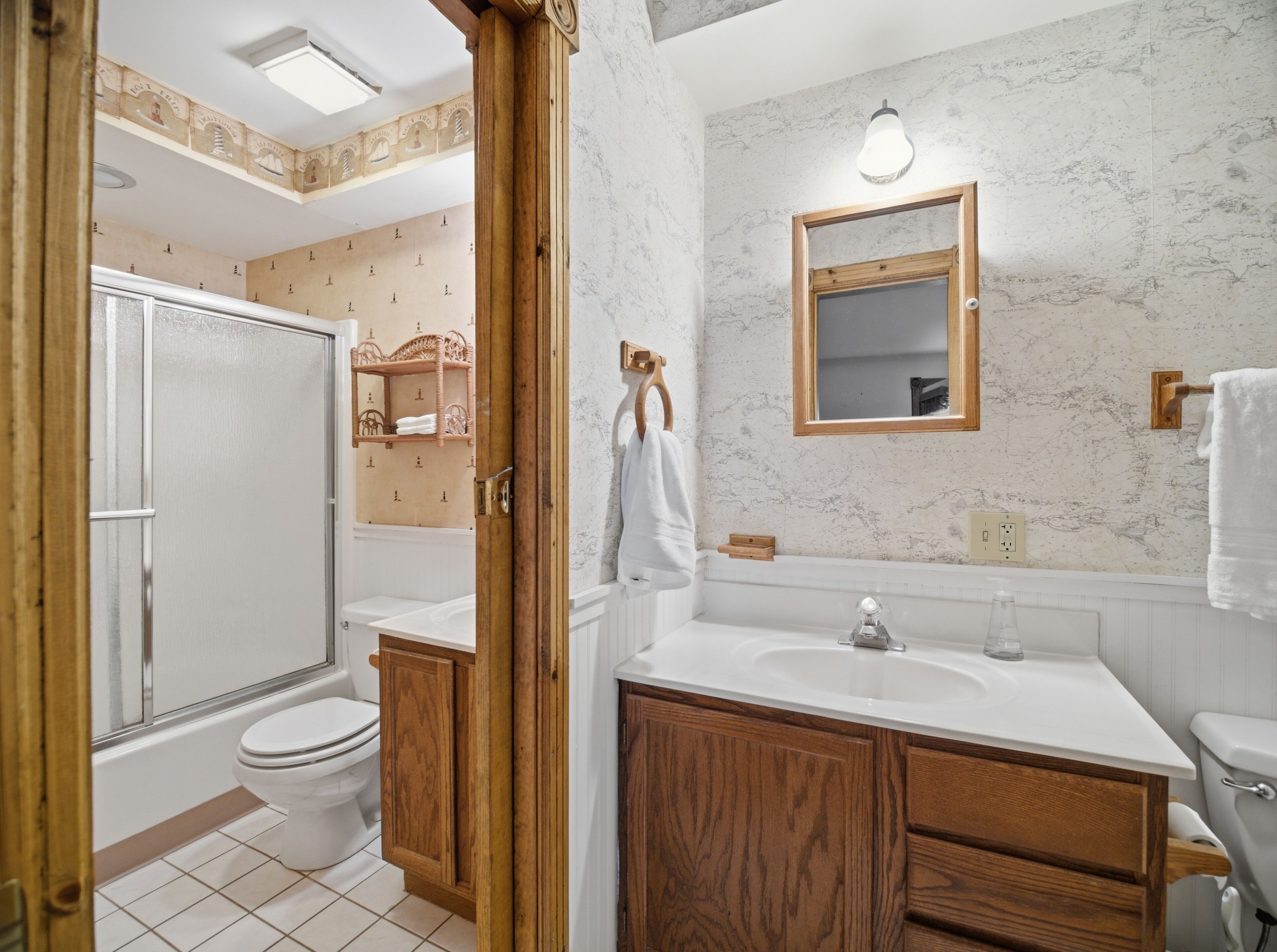 A bathroom with a toilet, sink, mirror, and wooden cabinets.