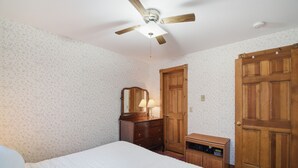 A bedroom with a bed, a wooden dresser, a mirror, a ceiling fan, and a door. - The Arlington GB: Charming Centrally Located Condo in Chautauqua Institution! (Chautauqua)