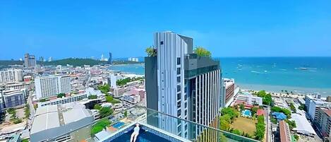 Un edificio alto con piscina en la azotea y vistas a la ciudad y al mar.