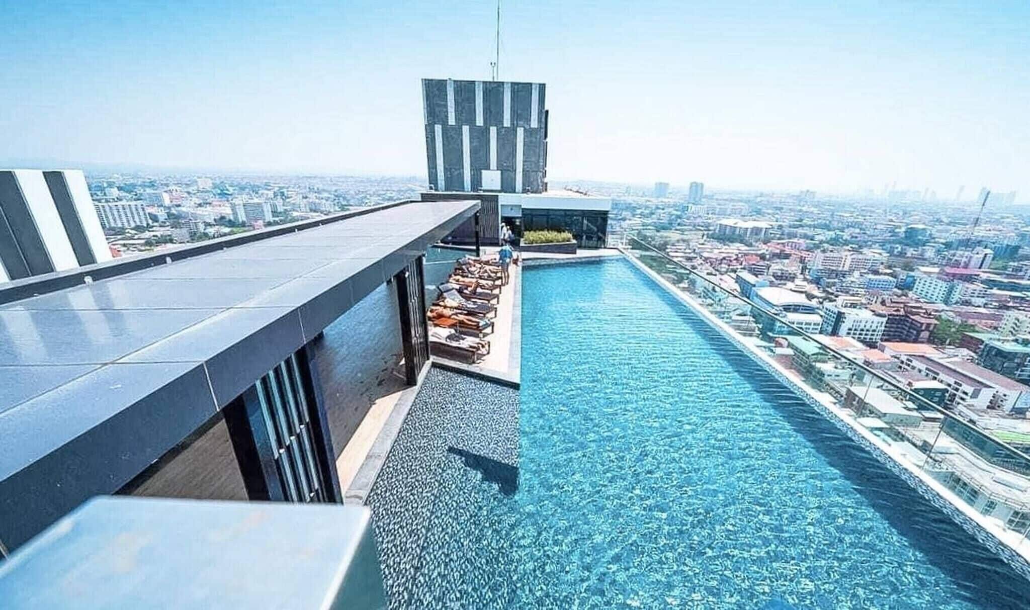 Piscina en la azotea con sillones de descanso y vistas a la ciudad.