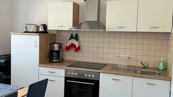 Eine moderne Küche mit weißen Schränken, einem Herd, einem Backofen und einer Kaffeemaschine.