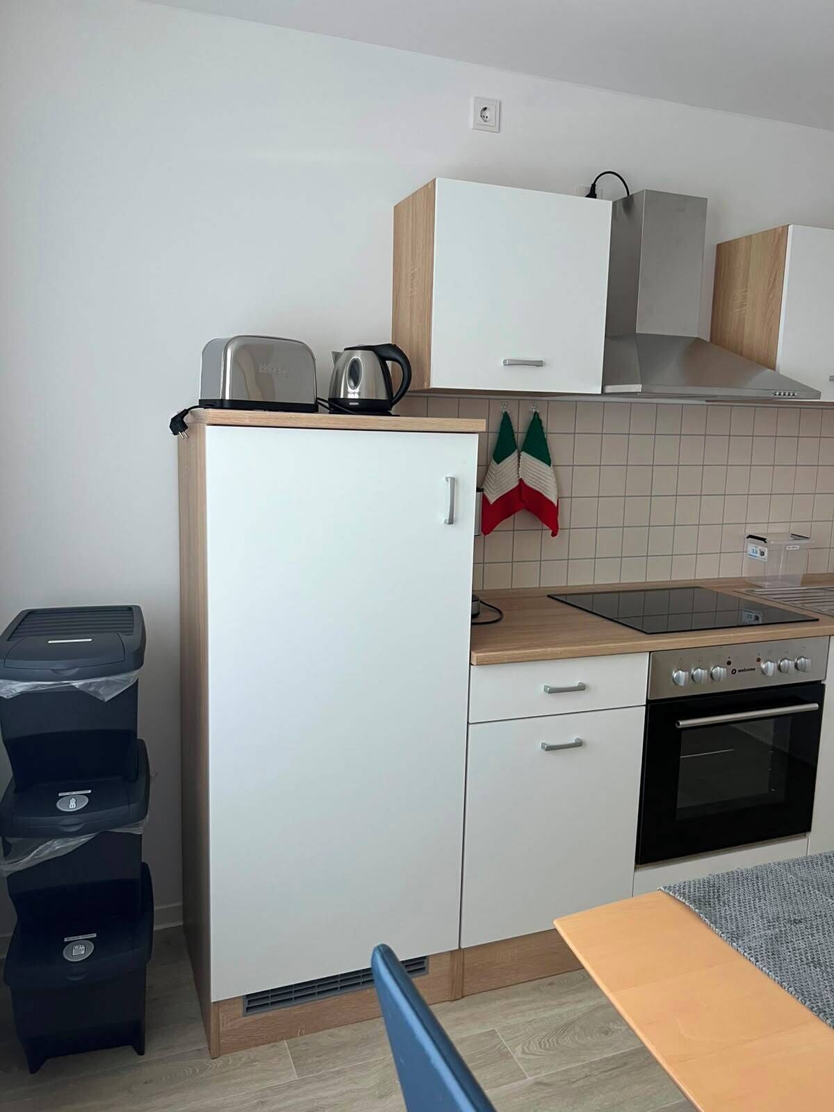 Una cocina compacta con horno integrado, estufa y un refrigerador pequeño.