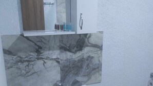 A bathroom with a white sink, marble backsplash, and a mirror above it. - ALPEDE (Zestafoni)