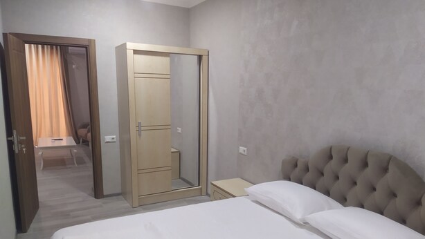 A bedroom with a bed, a wardrobe, a nightstand, and a chair. - ALPEDE (Zestafoni)