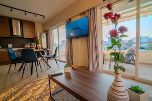 A modern living room with a dining area, a flat-screen TV, and a balcony with a city view. - 4.97 Super Host`s New Boutique & Prime Location (Limassol)