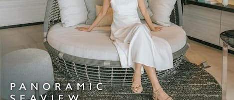 A woman sitting in a circular, woven chair with cushions, in a room with shelves and a rug.