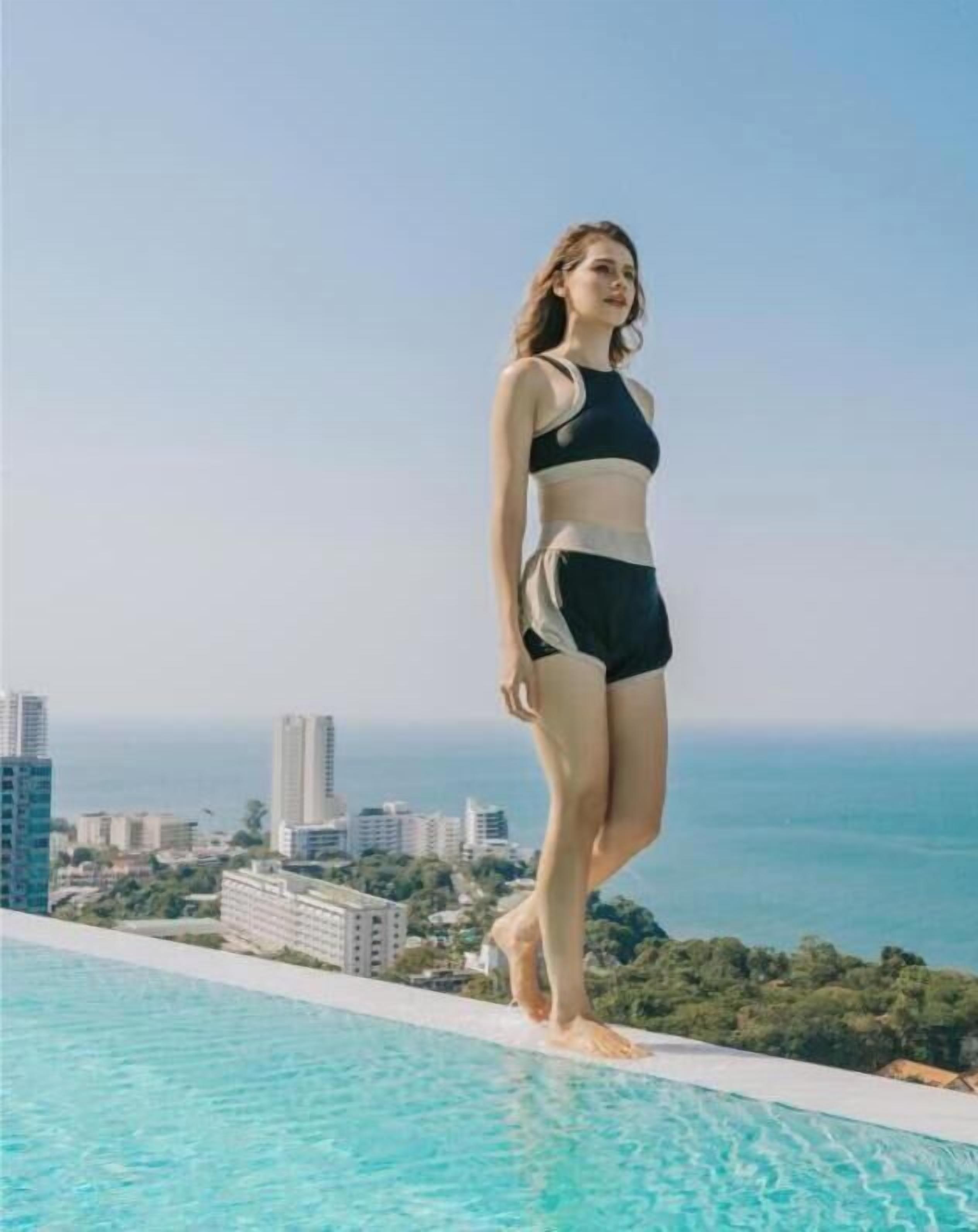 A person standing by a pool with a cityscape in the background.