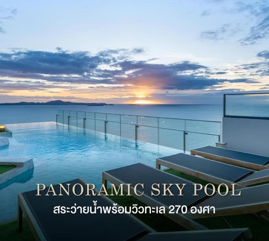 A panoramic sky pool with a sunset view, lounge chairs, and a glass railing.