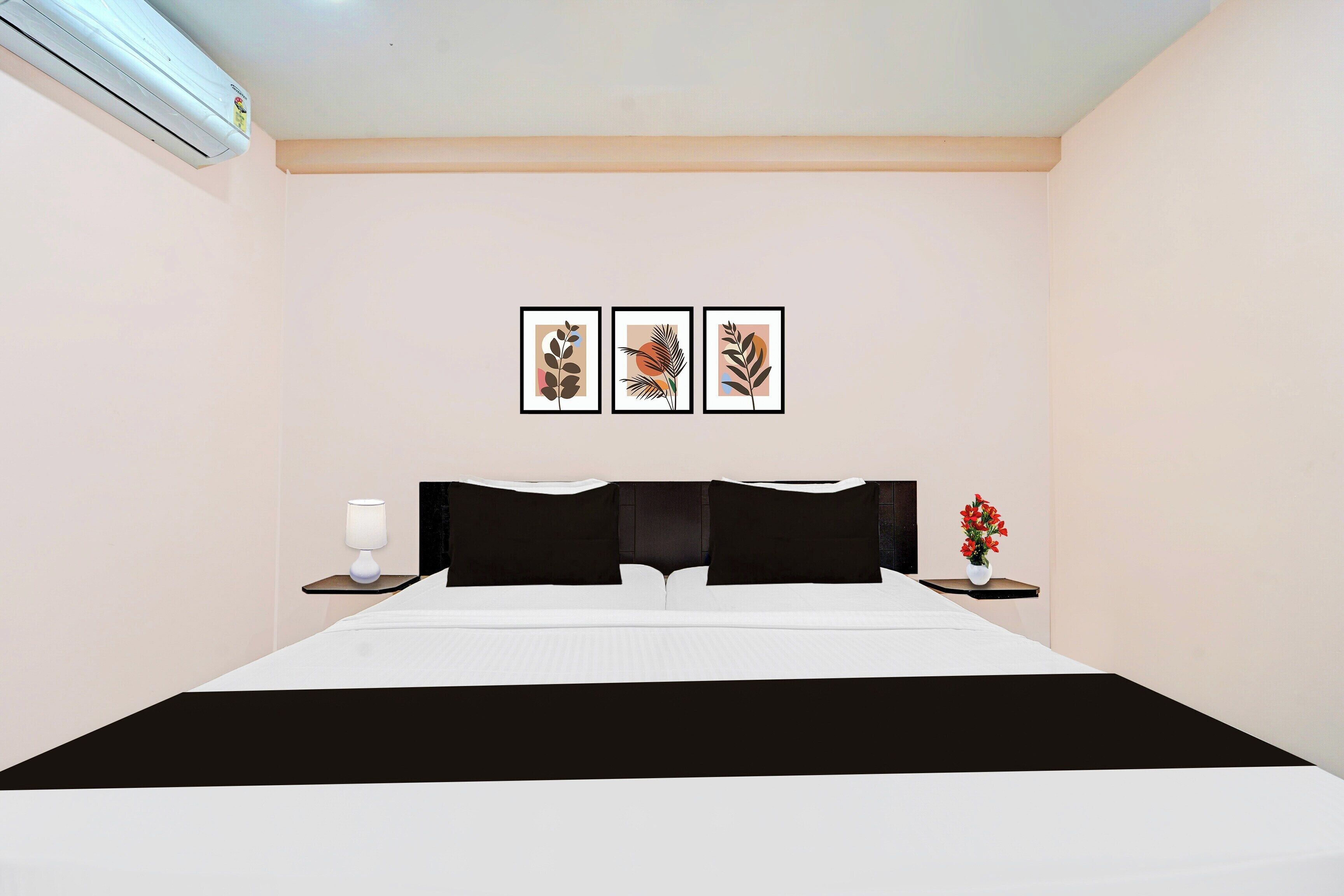 A hotel room with a bed, bedside tables, a lamp, and wall art.