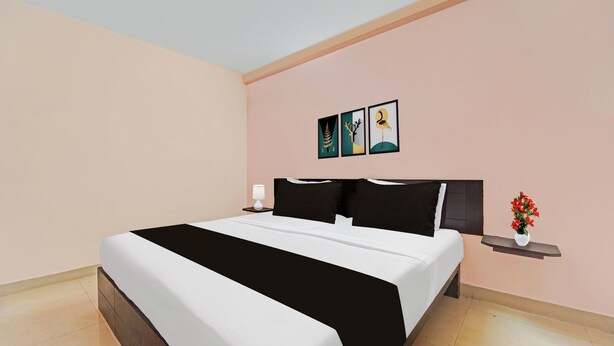 Una habitación de hotel con cama, mesita de noche, lámpara y un cuadro colgado en la pared.
