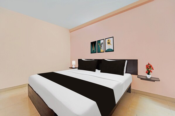 A hotel room with a bed, a nightstand, a lamp, and a wall-mounted picture.