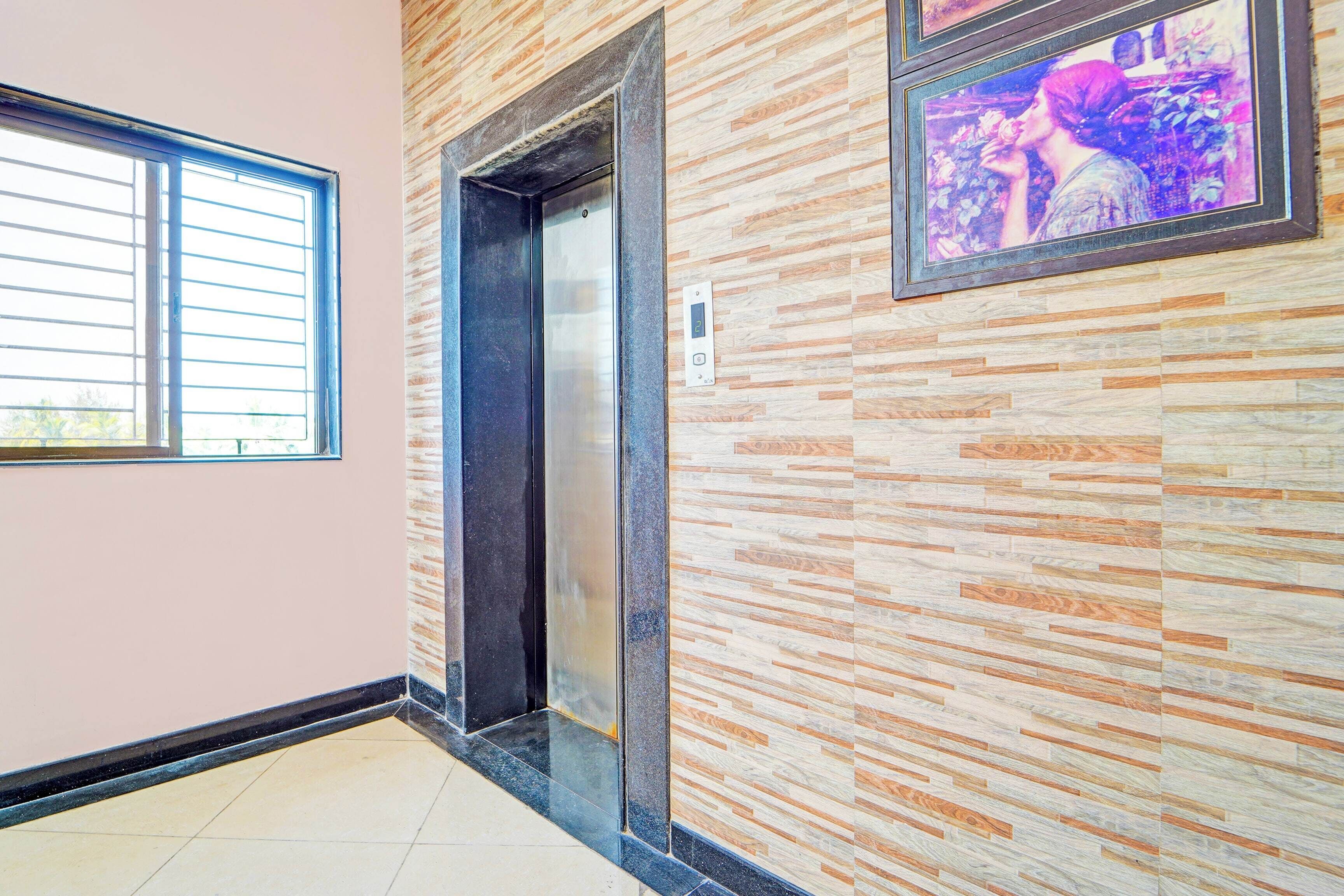 A hallway with a tiled floor, a door, and a wall-mounted elevator.