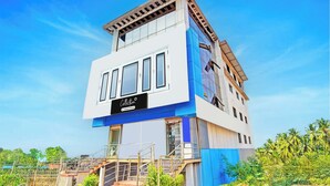 Un edificio moderno de varios pisos con un llamativo letrero que dice 'Collection', amplias ventanas y una escalera que conduce a la entrada.